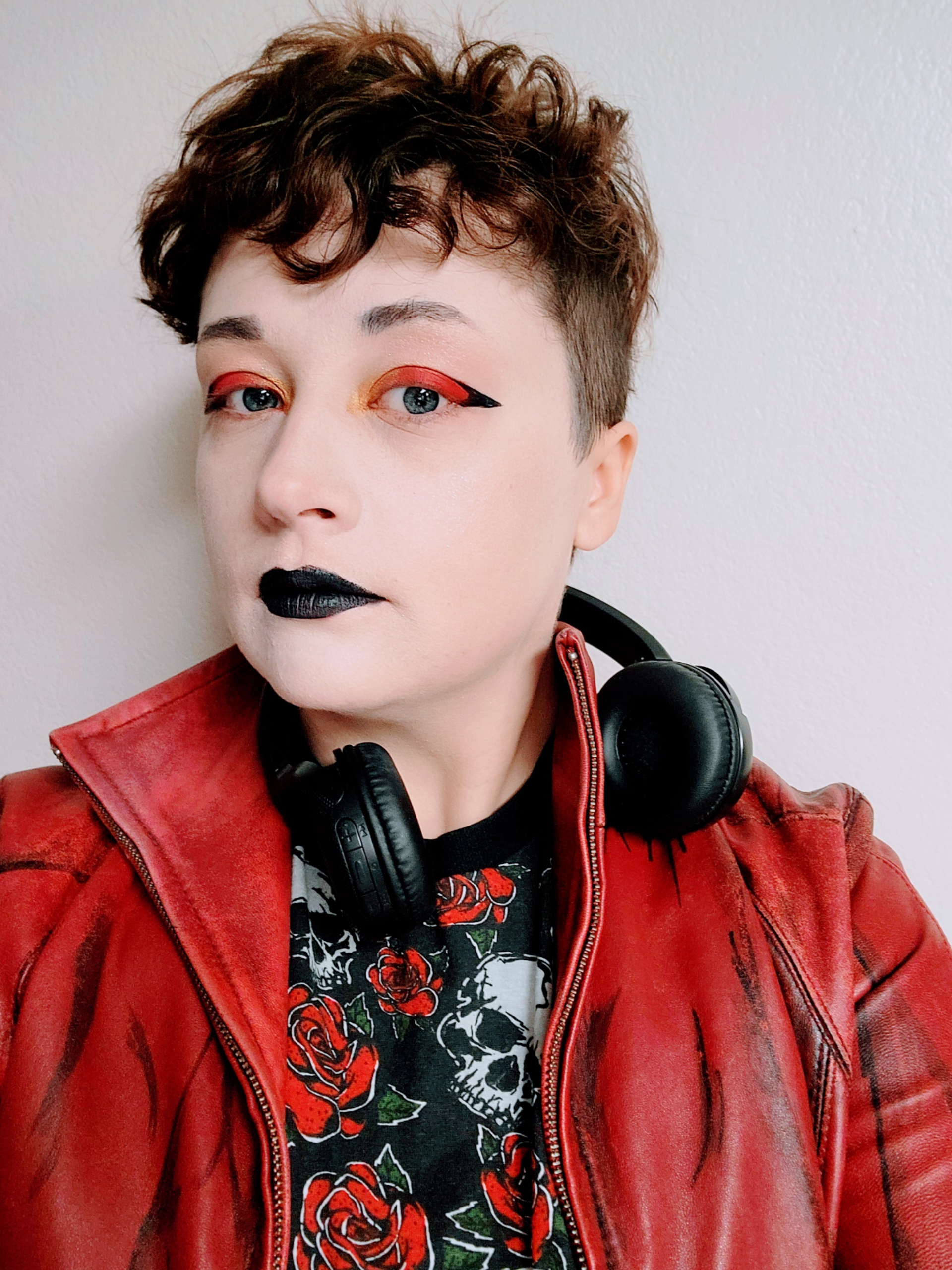 Artist Alejandro in a red and black outfit as well as makeup. 